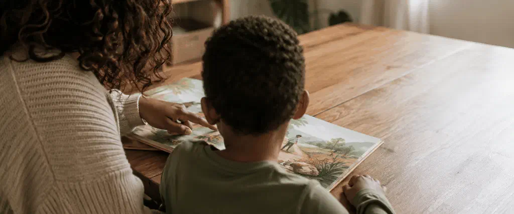 Child reading with a parent at home, with the child's face turned away