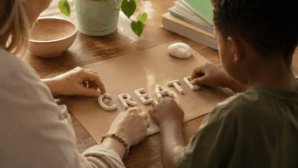 Parent and child working with modelling clay at a table, learning through a hands-on activity