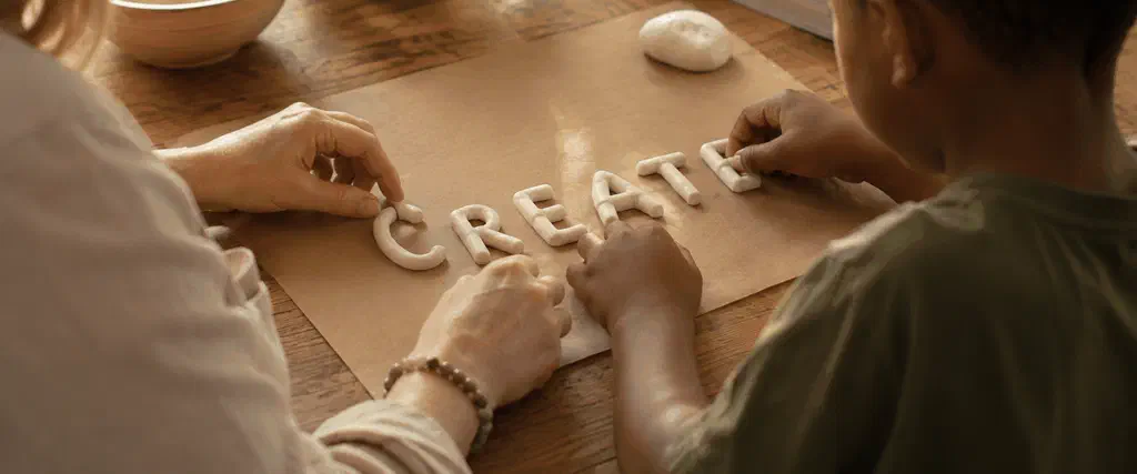 Parent and child working with modelling clay at a table, learning through a hands-on activity